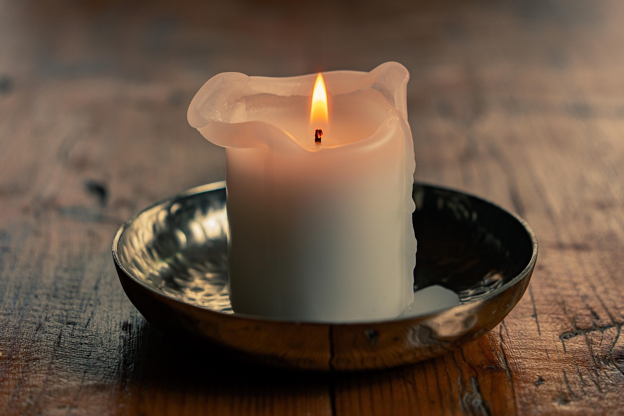 a burning white candle in a bowl