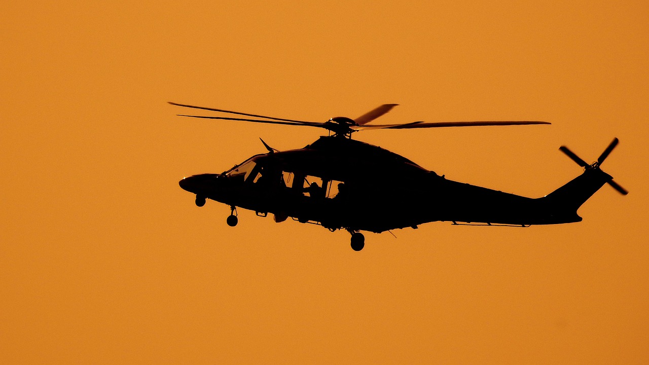 silhouette of a flying helicopter during sunset