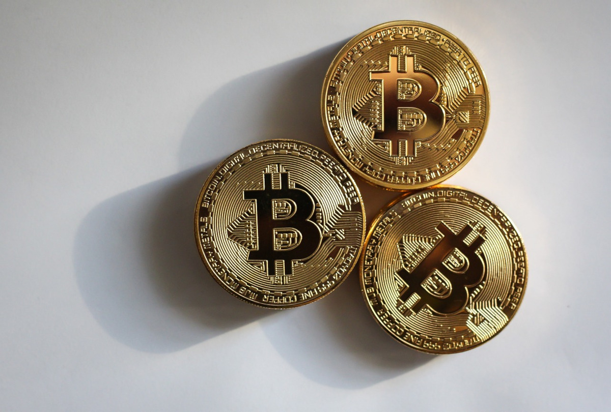 three bitcoins on a grey background