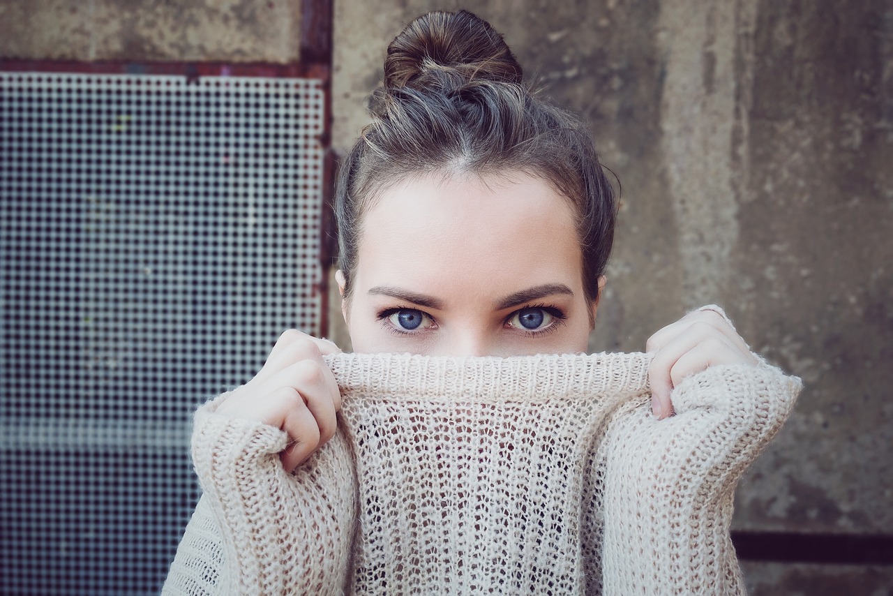 woman holding a knitwear sweater over her face